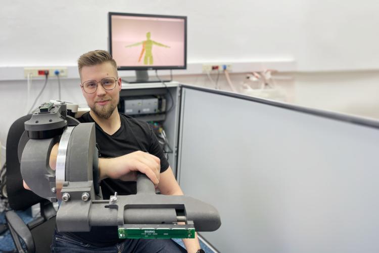 Na zdjęciu Piotr Falkowski z założonym na rękę prototypem egzoszkieletu