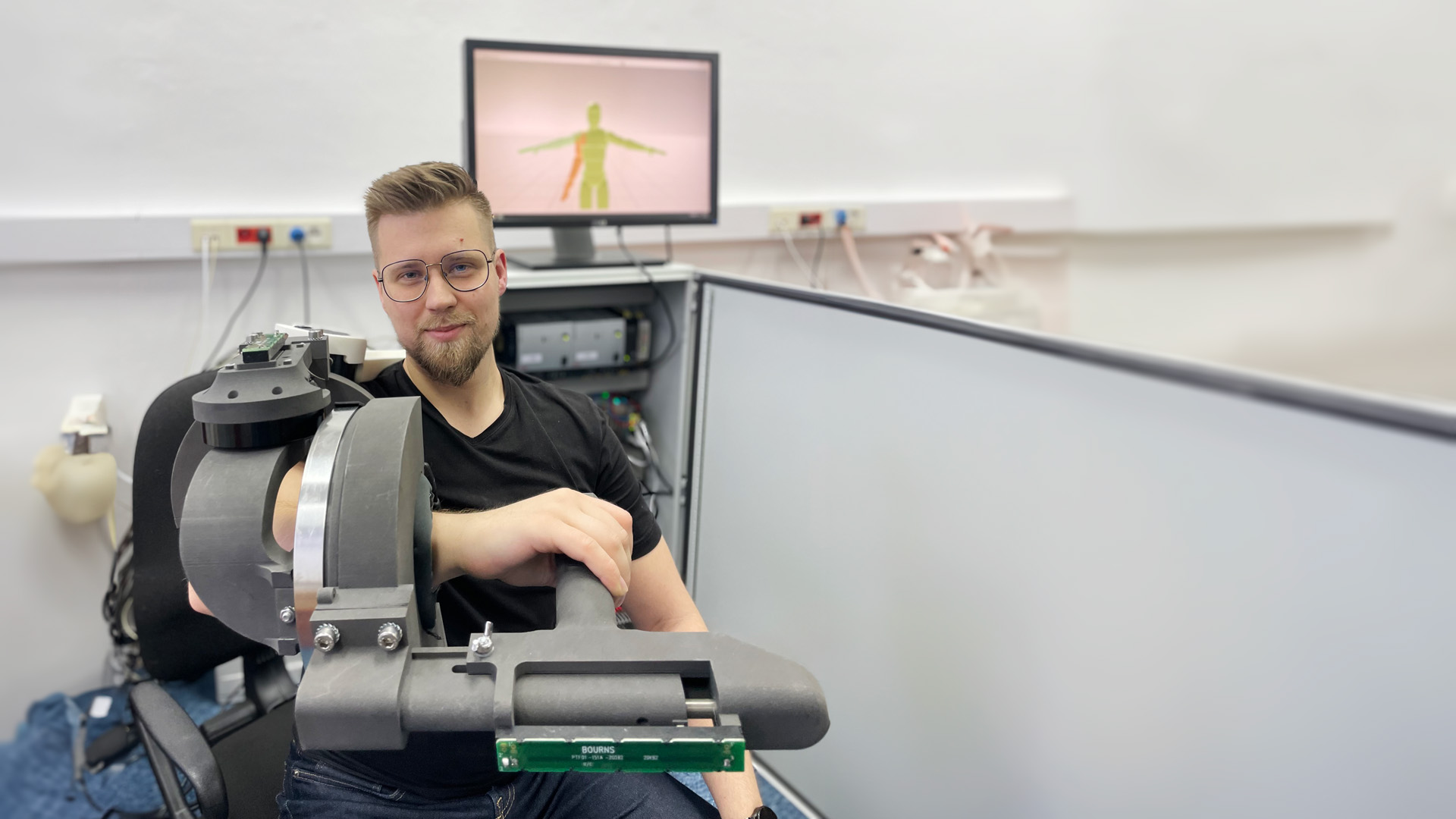 Na zdjęciu Piotr Falkowski z założonym na rękę prototypem egzoszkieletu