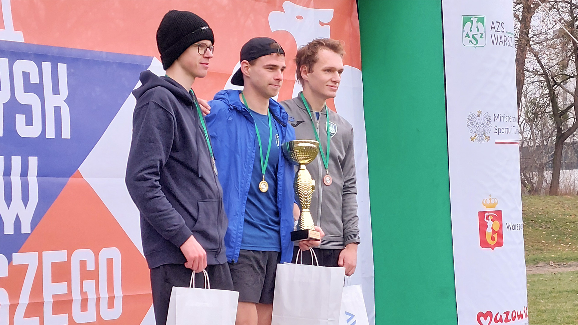 Trzej studenci stoją na podium z nagrodami