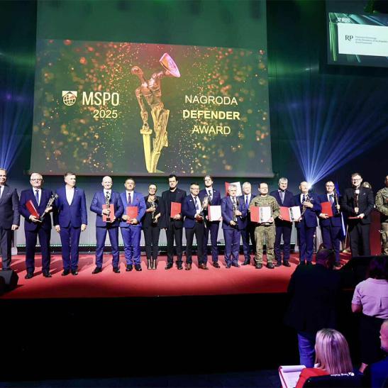 Na zdjęciu grupa ludzi na scenie - laureaci nagrody Defender