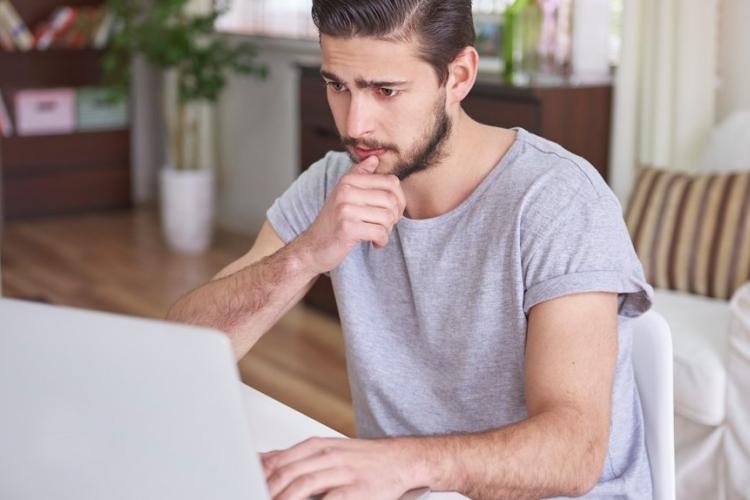 Zdjęcie mężczyzny siedzącego przed ekranem laptopa
