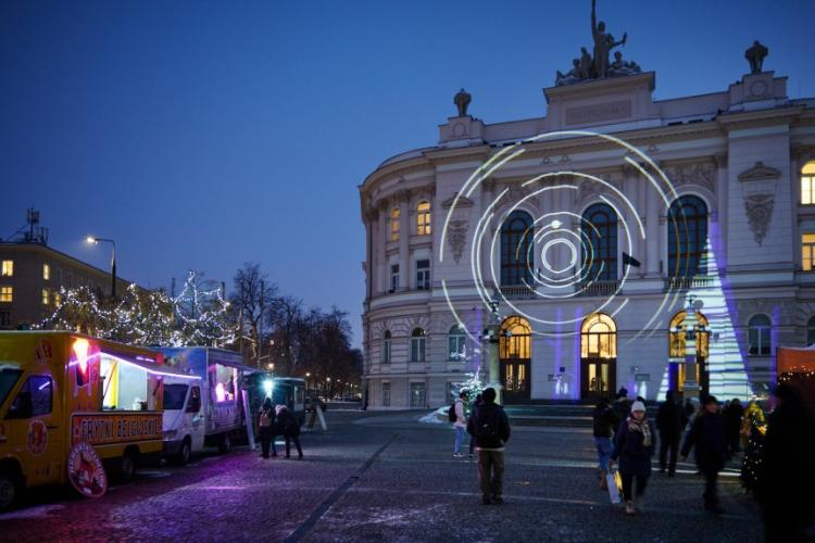 Zdjęcie Gmachu Głównego Politechniki Warszawskiej ze świąteczną iluminacją i ludźmi uczestniczącymi w kiermaszu