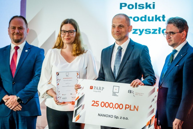 Zdjęcie przedstawicieli firmy Nanoxo pozujących z czekiem za wyróżnienie w konkursie Polski Produkt Przyszłości oraz wręczających nagrody 