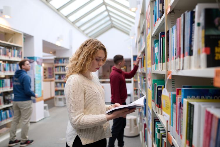 Studenci szukający książek w bibliotece