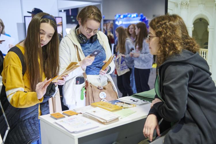Na zdjęciu trzy osoby rozmawiające przy stoisku Politechniki na Międzynarodowym Salonie Edukacyjnym