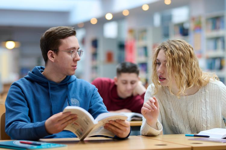 Na zdjęciu troje studentów siedzących w Bibliotece Politechnice Warszawskiej