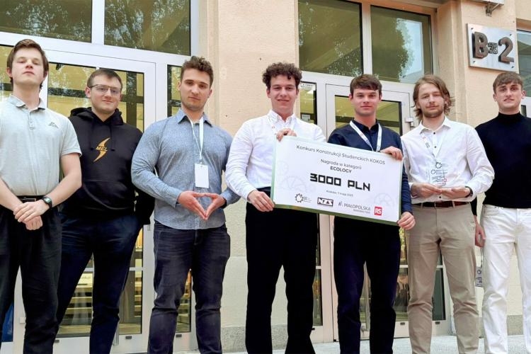 Na zdjęciu siedmiu studentów stojących na tle budynku
