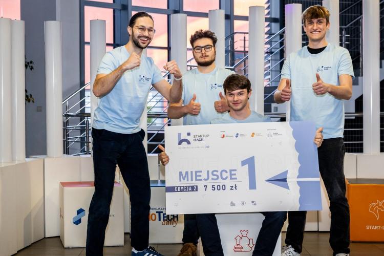 Na zdjęciu czterej młodzi mężczyźni z czekiem za zwycięstwo w Hackathonie StartupHack