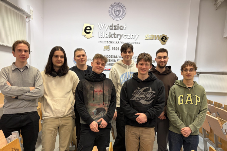 Zdjęcie przedstawia ośmiu studentów stojących na tle ściany z logotypem Wydziału Elektrycznego PW