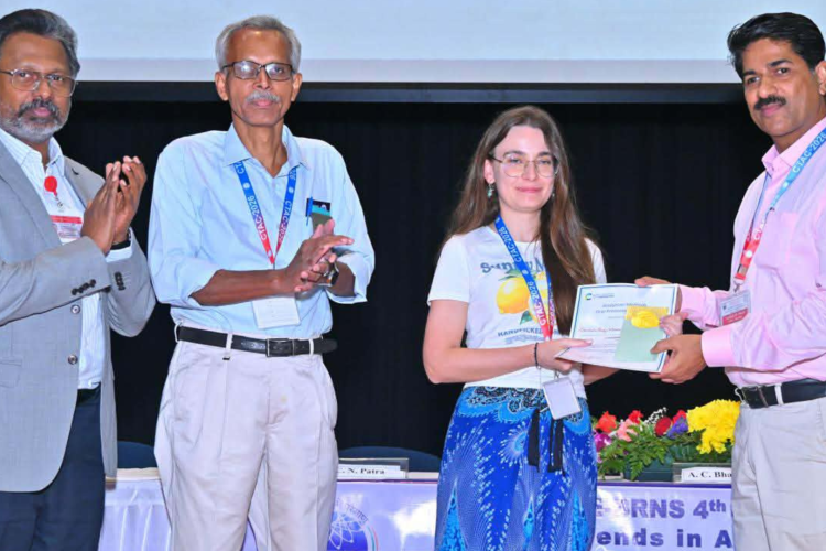 Na zdjęciu są 4 osoby. Jedna z nich, kobieta, odbiera dyplom