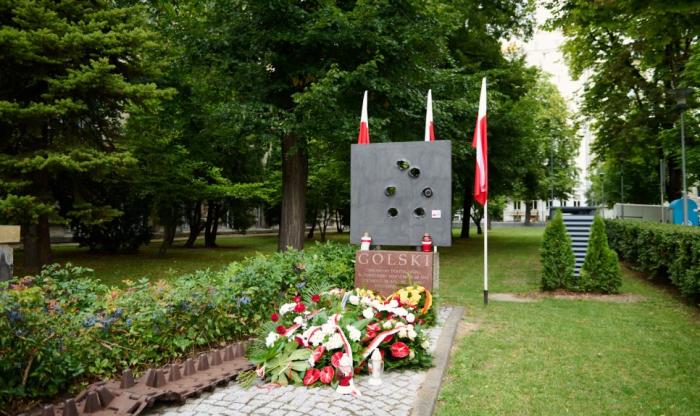 Zdjęcie pomnika batalionu "Golski" na terenie Politechniki Warszawskiej ze złożonymi kwiatami  zniczami