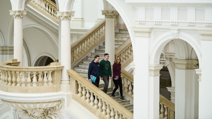 Na zdjęciu troje studentów idących po schodach w Gmachu Głównym PW