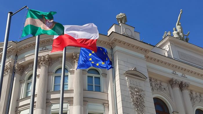 Na zdjęciu fragment Gmachu Głównego oraz wiszące przed nim flagi: Politechniki Warszawskiej, Polski, Unii Europejskiej 