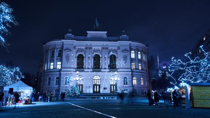 Na zdjęciu Gmach Główny PW po zmroku, ze świąteczną iluminacją i widocznymi domkami kiermaszowymi