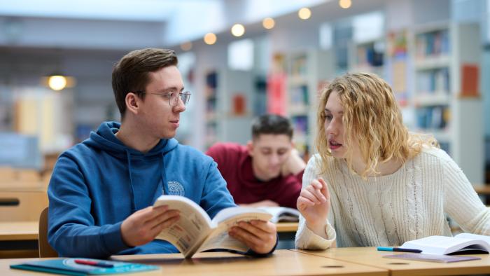 Na zdjęciu troje studentów siedzących w Bibliotece Politechnice Warszawskiej
