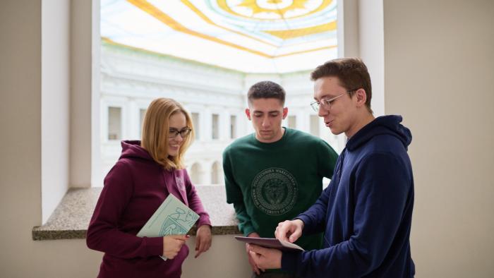 Studentka i studenci rozmawiający w Gmachu Głównym Politechniki Warszawskiej