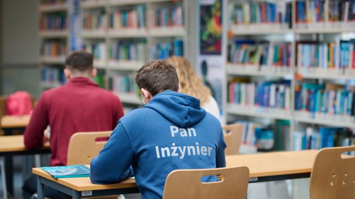 Na zdjęciu troje studentów siedzących w ławkach w Bibliotece Głównej
