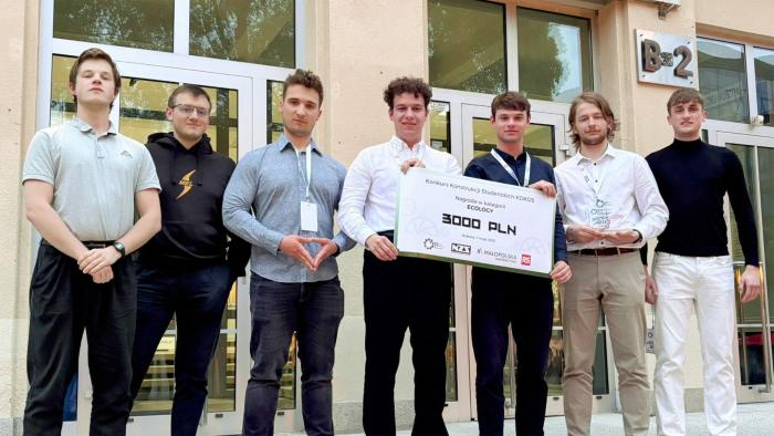 Na zdjęciu siedmiu studentów stojących na tle budynku