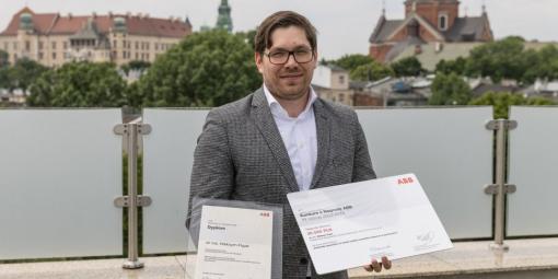 Dr inż. Maksym Figat trzymający dyplom i czek za wygraną w konkursie