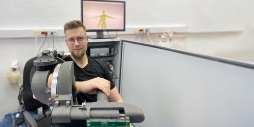 Na zdjęciu jeden z twórców rozwiązania - Piotr Falkowski z założonym na rękę prototypem egzoszkieletu