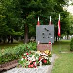 Zdjęcie pomnika batalionu "Golski" na terenie Politechniki Warszawskiej ze złożonymi kwiatami  zniczami