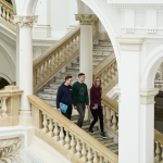Na zdjęciu troje studentów idących po schodach w Gmachu Głównym PW