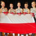 Na zdjęciu siedem zawodniczek z sekcji aerobiku sportowego. Stoją, trzymając przed sobą flagę Polski