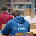 Na zdjęciu trzy osoby (widziane od tyłu) siedzące przy stolikach w Bibliotece Głównej PW