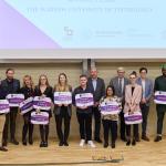 Na zdjęciu dziesięcioro finalistów konkursu 3MT na Politechnice Warszawskiej, jurorzy oraz prowadzący. Wszyscy stoją na scenie