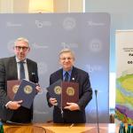 Za zdjęciu prof. Mariusz Malinowski oraz prof. Krzysztof Szmałek trzymający podpisane umowy, stojący na tle ścianki i roll-upu